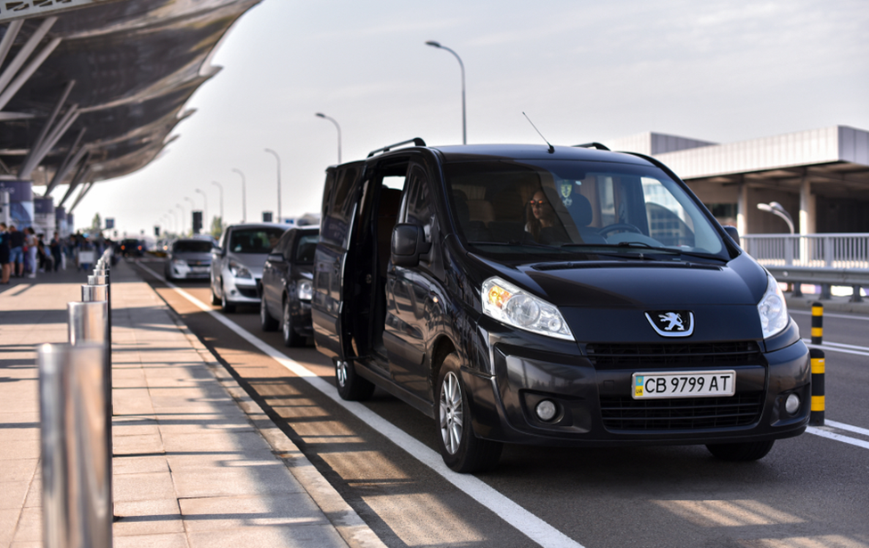 A black van doing Airport Transfer passengers.